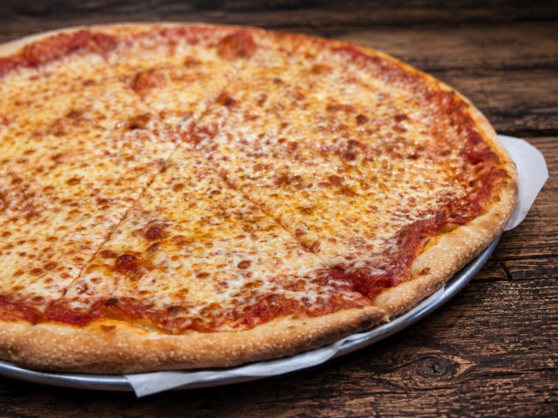 A classic cheese pizza with a crispy crust, sliced and ready to eat on a wooden table.